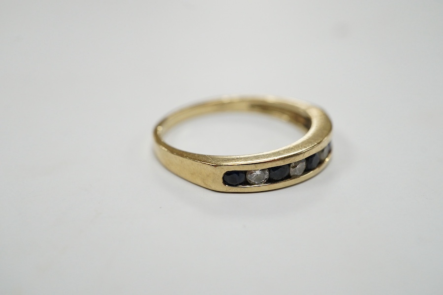 A modern 9ct gold and channel set sapphire and diamond set half hoop ring, size N/O, gross weight 2.2 grams. Condition - fair